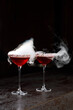two glasses of red cocktail with smoke
