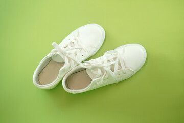 A pair of new white sneakers on green background. Shoes