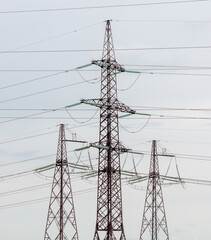 Metal electric poles against a gray sky with clouds