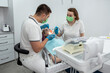 © RomanR - male dentist and a female assistant treat a patient.