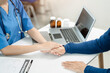 © NINENII - Friendly female doctor hands holding patient hand sitting at the desk for encouragement, empathy, cheering and support while medical examination.