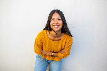 smiling young woman with arms crossed by white background