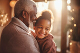 Fototapeta  - An elderly man with a little girl in the room. They hug, have fun and rejoice at the meeting. A little granddaughter and her grandfather are sitting on the sofa and hugging. Caring for the elderly.