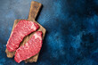 © Vladimir - Alternative beef steak Denver, raw meat steak on a wooden board. Blue background. Top view. Copy space