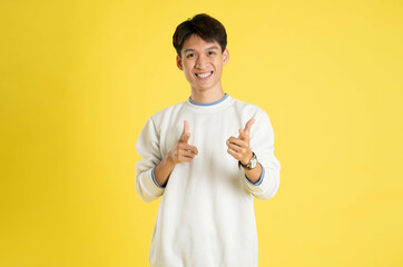 Wall Mural - Portrait of young Asian man wearing sweater and posing on yellow background