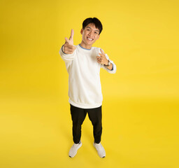 Wall Mural - full body of young Asian man wearing sweater and posing on yellow background