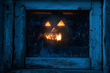 Wall Mural - scary Halloween pumpkin glowing in window at night