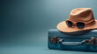 A blue suitcase with hat and sunglasses isolated on blue background with copyspace. summer, travel and vacation concept