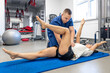 © puhimec - Woman doing gymnastics with help of his young physical therapist.