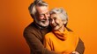 Un couple de personnes âgées, seniors heureux, fond coloré orange