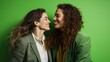 Un couple de femmes brunes aux cheveux longs, lesbiennes, homosexuelles, âgé de 30 ans, souriante, arrière-plan vert.