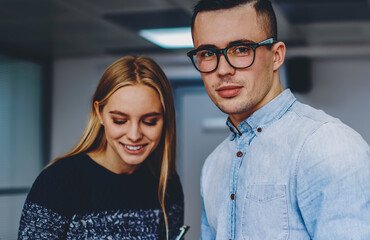 Canvas Print - Portrait of good looking young man dressed in denim shirt looking at camera while positive female