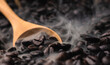 close-up of pile of coffee beans in wooden scoop with smoke