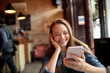 © Geber86 - Happy young caucasian woman using her phone in a indoor cafe in the city