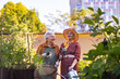 © Halfpoint - Portrait of senior friends taking care of vegetable plants in urban garden.
