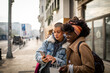 © Marko Geber - Young mixed lesbian couple using a smartphone together while shopping in the city