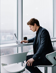 Serious proud ceo reading information from web page browsed on laptop computer during job
