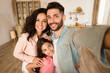 © Prostock-studio - Family selfie. Happy father, mother and their daughter taking photo, parents and child girl posing and smiling at camera