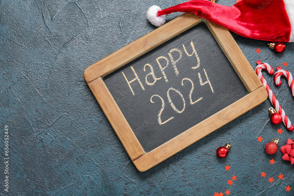 Blackboard with text HAPPY 2024 and Christmas decorations on dark grunge background