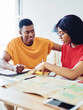 © BullRun - Smiling african american hipster guy looking at his pretty girlfriend making plan of trip using map
