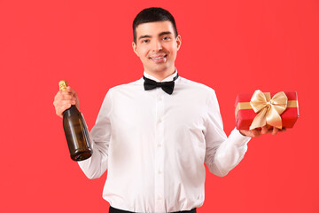 Sticker - Young man with champagne and Christmas gift on red background