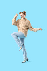 Poster - Happy beautiful young woman in warm sweater and eyeglasses on blue background