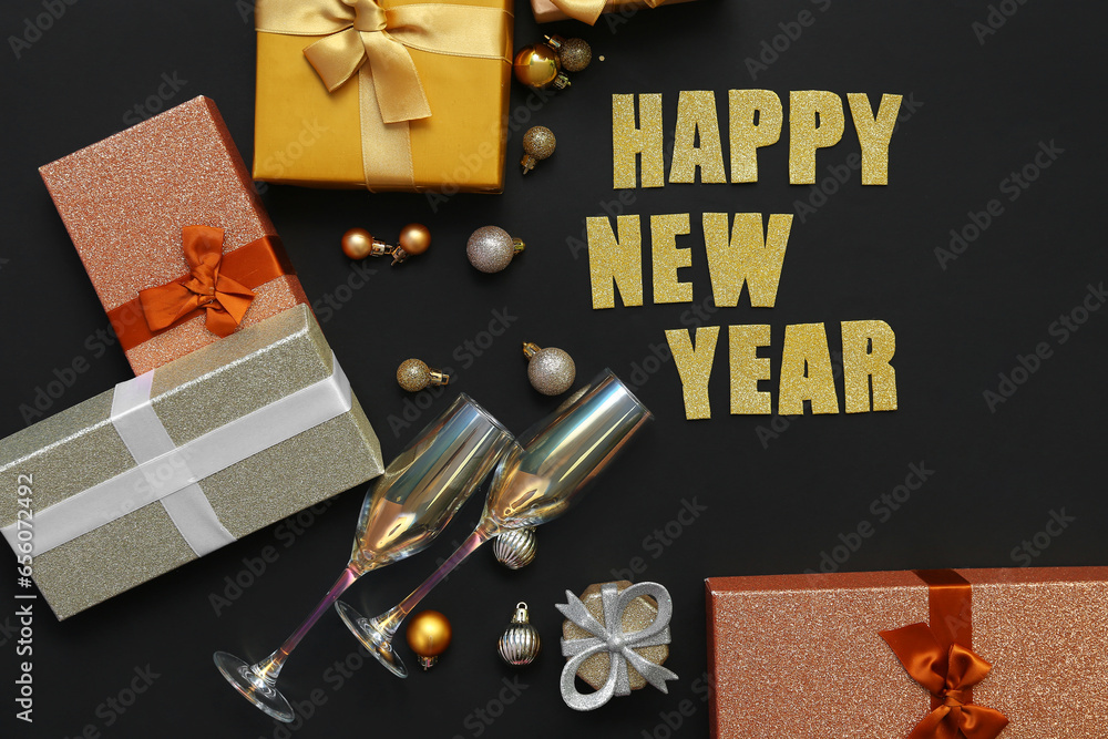 Text HAPPY NEW YEAR with Christmas balls, glasses and gift boxes on black background
