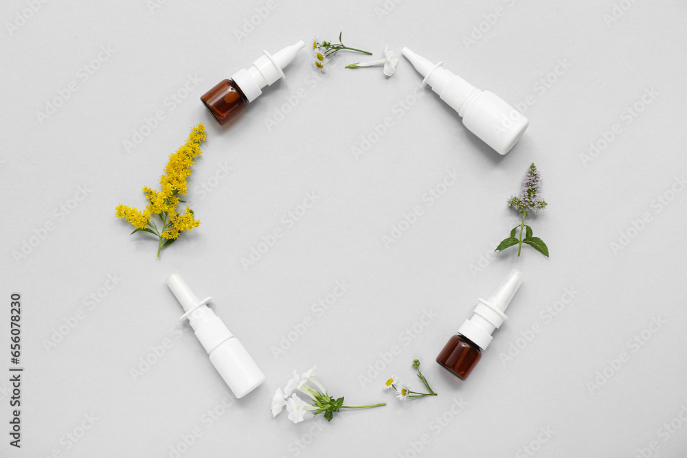 Frame made of nasal drops and different flowers on grey background