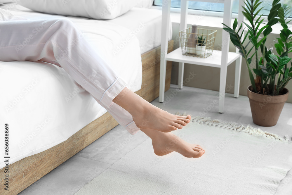 Barefoot woman in bedroom with floor heating, closeup
