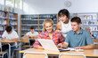 © JackF - Smiling teenage boy and girls using laptop at college library, watching videos