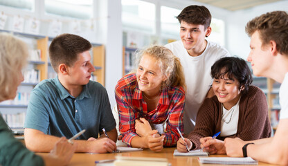 Wall Mural - Brainstorming teen students in the school library