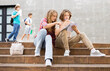 © JackF - Two teenage students discussing while sitting with workbooks near college building on autumn day