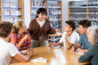 © JackF - Group of fifteen-year-old schoolchildren with a female teacher are discussing something in the school library during an extracurricular lesson