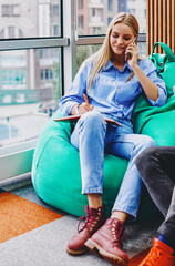 Canvas Print - Hipster girl calling on smartphone and noting information in notebook