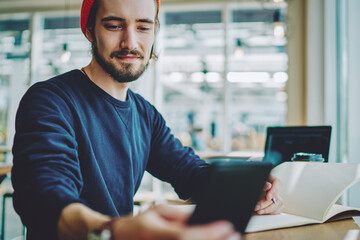 Wall Mural -  positive hipster guy checking notification on cellular phone