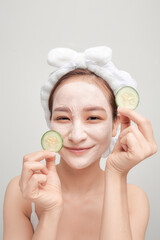 Wall Mural - Young woman applying clay mask on her mask with sliced fruit in hand over color banner