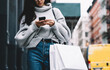 © BullRun - Trendy young woman browsing on mobile at street