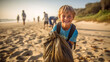 © JKLoma - Young boy volunteer smiling looking at a camera picking up a plastic litter on a beach.