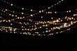 Gold Twinkle Christmas string lights on black background. Defocused Glowing light bulb garland. Generative AI