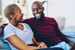 © BullRun - smiling dark skinned man hugging his wife having conversation on leisure in living room