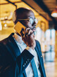 © BullRun - Experienced dark skinned proud ceo in black suit talking on telephone device