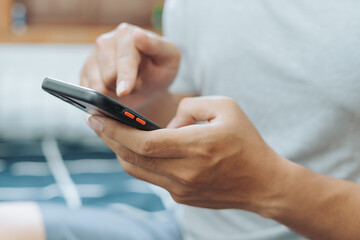Hands of Asian man holding checking touching scrolling smartphone from bed room