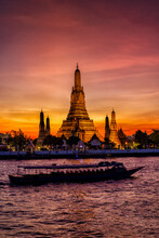The Famous Buddhist Temple Wat Arun During Dusk With Boat Traffic On The Chao Phraya Rriver, Bangkok, Thailand