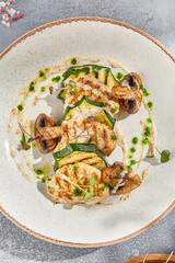 Sticker - Close-up top view of a health-centric grilled turkey fillet steak with zucchini and mushrooms. The meal is set on a white ceramic plate and has a grey concrete background for a minimalist touch