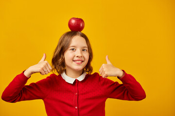 Stylish smiling school teenage girl holding appleson her head