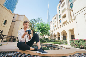 Wall Mural - Enjoying travel in United Arabian Emirates. Happy young woman with camera taking photo in Dubai Downtown.