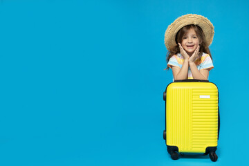 Wall Mural - A little girl in a beach hat with a suitcase