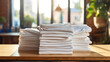 © red_orange_stock - A stack of folded tshirts on wooden table. Laundromat is illuminated by the soft afternoon sun shining through the window.