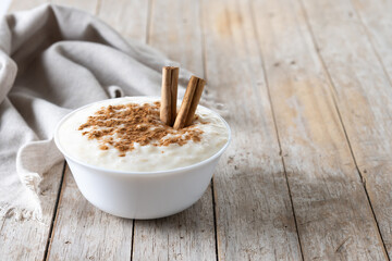 Wall Mural - Arroz con leche. Rice pudding with cinnamon in bowl on wooden table. Copy space