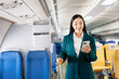 © Nuttapong punna - Portrait of  successful Asian businesswoman or entrepreneur in a formal suit on an airplane sitting in business class using a phone, computer laptop. Travel in style, work with grace...
